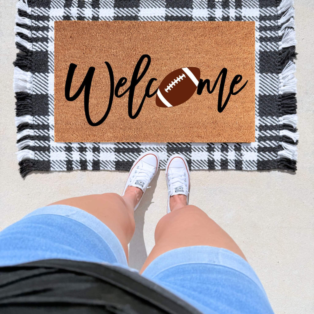 Football welcome doormat featuring the word "Welcome" with a football design on a natural coir welcome mat for football fans and game day front porch décor.